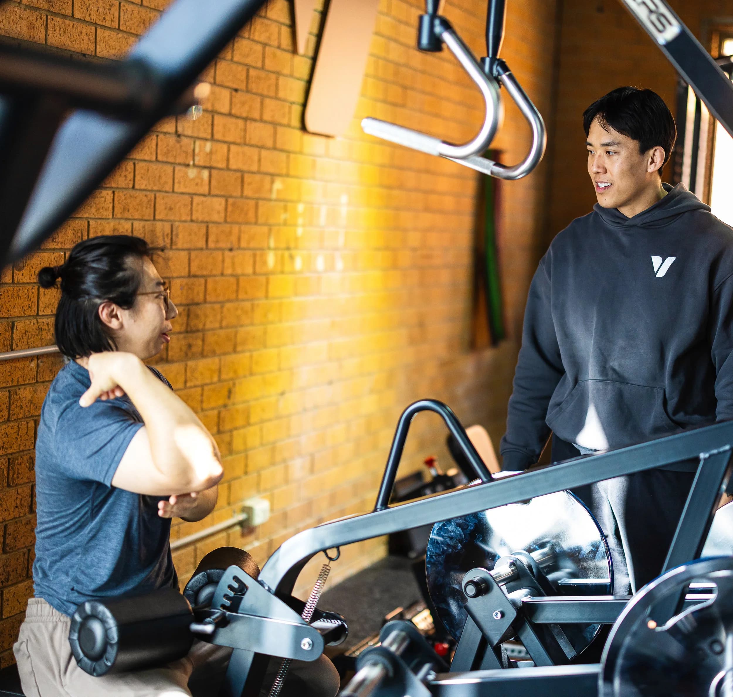 Khoi coaching a client on a machine against the brick wall